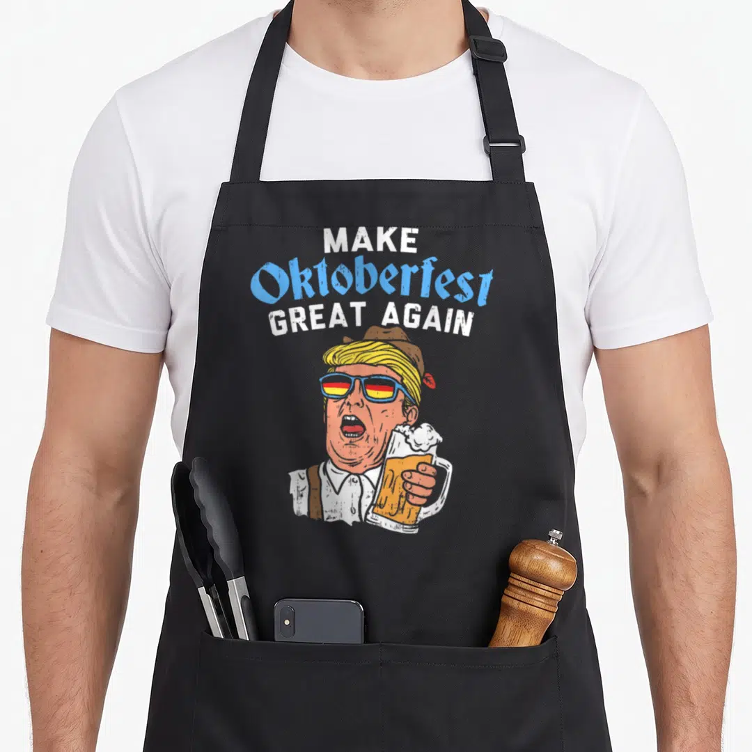 Oktoberfest beer apron - Cartoon Donald Trump holding beer mug under Make Oktoberfest Great Again text in blue and white — shown on a black cotton canvas apron against a white background