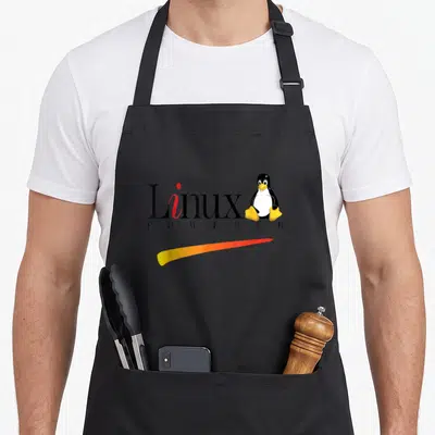 Linux penguin aprons - Cartoon penguin sitting next to Linux text with gradient swoosh — shown on a black cotton canvas apron against a white background