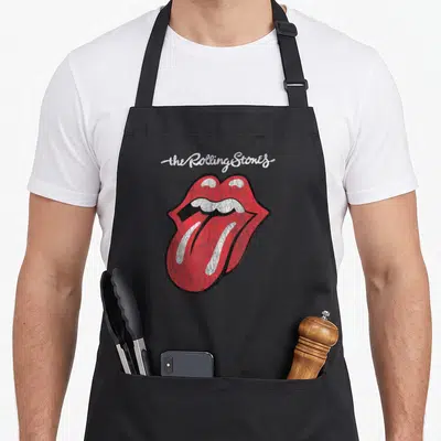 Script rolling stones apron - Distressed red mouth with tongue and white script text on grey background — shown on a black cotton canvas apron against a white background