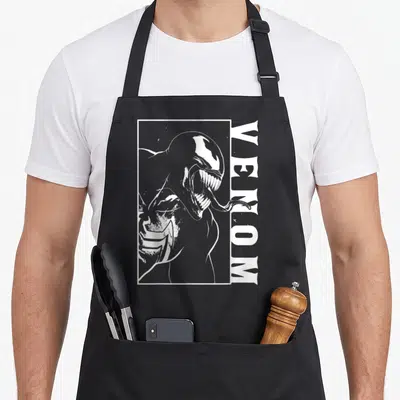 View comics apron - White line art Venom character in a rectangular frame with vertical text on black fabric — shown on a black cotton canvas apron against a white background