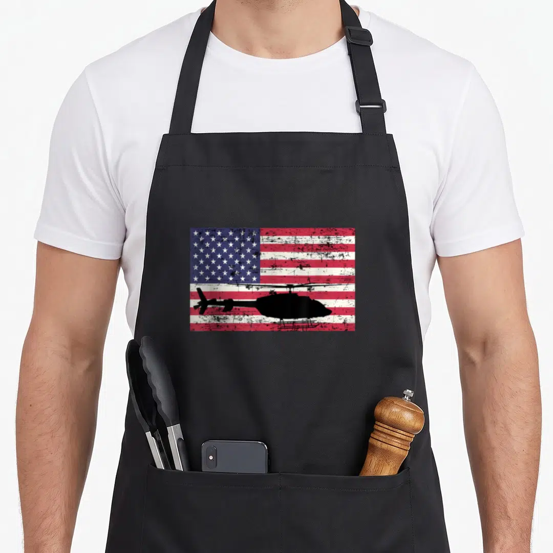 Bell american flag apron - Black helicopter silhouette over distressed red white and blue American flag pattern — shown on a black cotton canvas apron against a white background