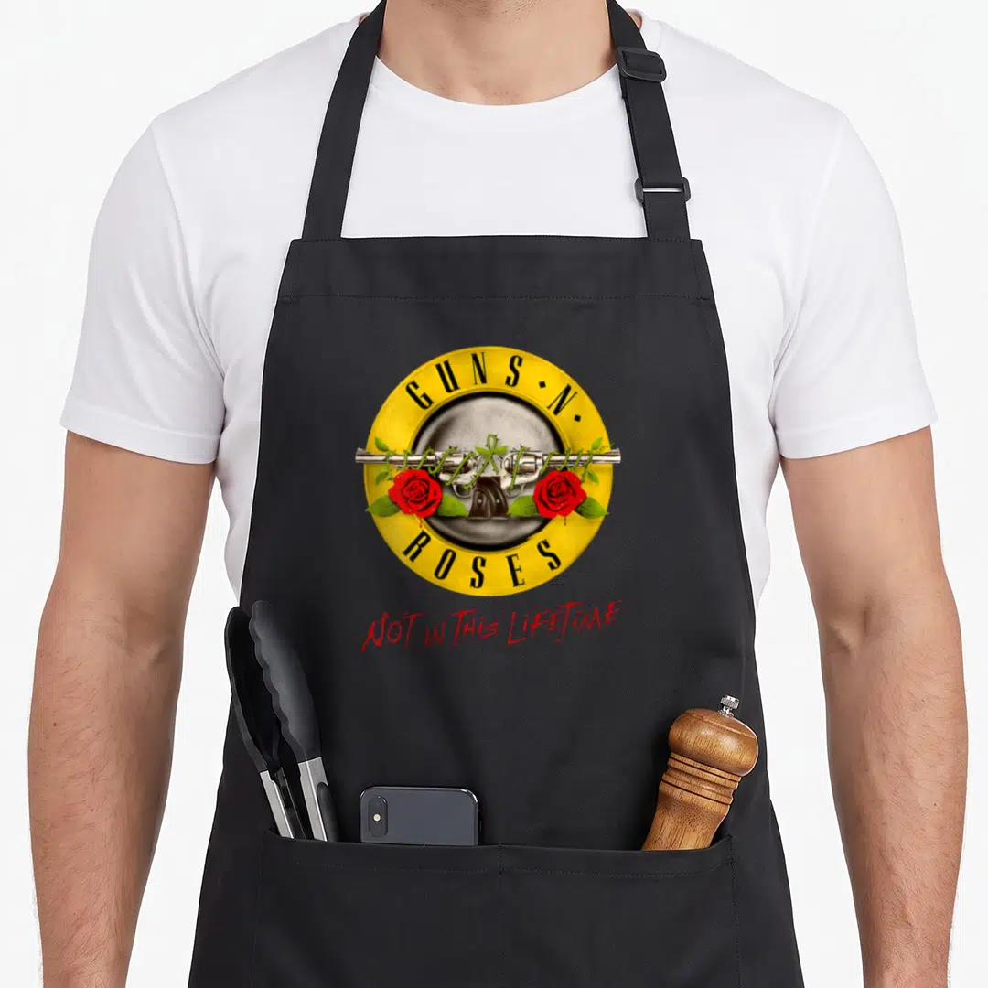 Rose lifetime gun apron - Yellow circle with revolvers, red roses, and Guns N Roses text — shown on a black cotton canvas apron against a white background