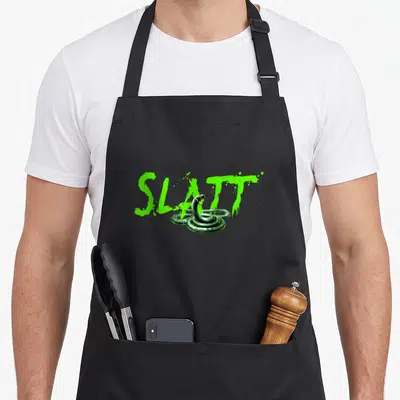 Slatt snake apron - Lime green splatter text SLATT with coiled dark green snake illustration — shown on a black cotton canvas apron against a white background