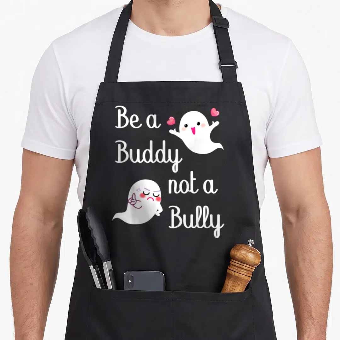 Bully buddy aprons - Be a Buddy not a Bully text with happy and angry white ghosts and pink hearts — shown on a black cotton canvas apron against a white background