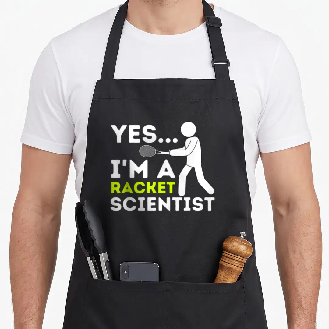 Racket scientist apron - White and lime text YES I'M A RACKET SCIENTIST next to stick figure holding racket — shown on a black cotton canvas apron against a white background