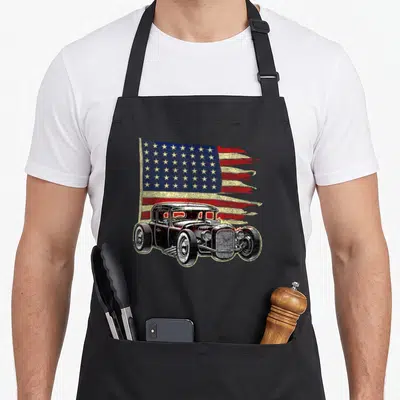 Rod tuning car apron - Distressed black hot rod overlapping tattered red white and blue USA flag — shown on a black cotton canvas apron against a white background