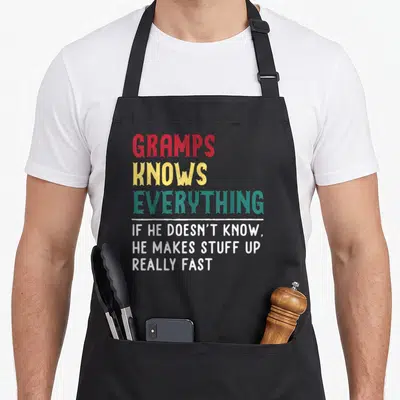 Gramp grandpa father day apron - Stacked text GRAMPS KNOWS EVERYTHING in red yellow teal white distressed font — shown on a black cotton canvas apron against a white background