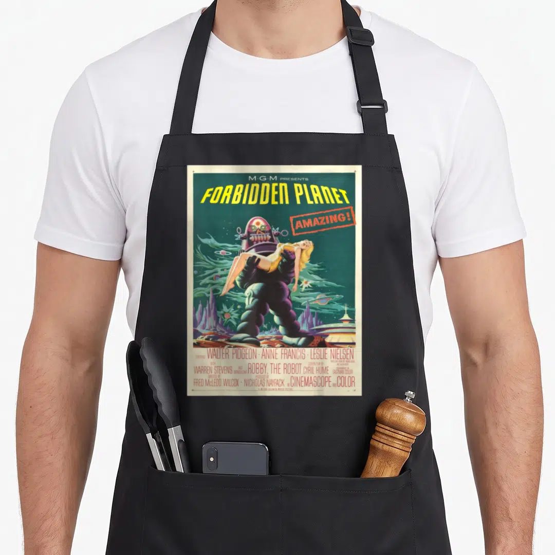 Forbidden cartoon apron - Robot carrying woman on Forbidden Planet poster with cast credits in retro colors — shown on a black cotton canvas apron against a white background
