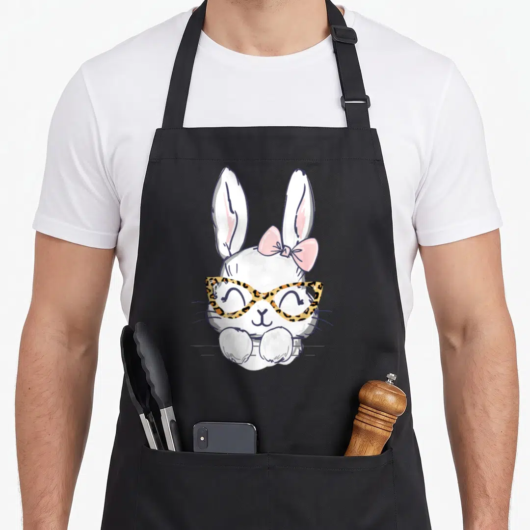 Cheetah easter bunny aprons - Cartoon white rabbit peeking over line wearing leopard glasses and pink bow — shown on a black cotton canvas apron against a white background
