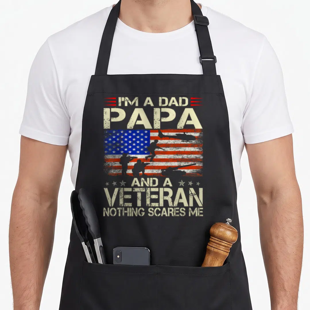 Veteran grandpa apron - Distressed USA flag with soldier and helicopter silhouettes, stacked text reading I'M A DAD — shown on a black cotton canvas apron against a white background