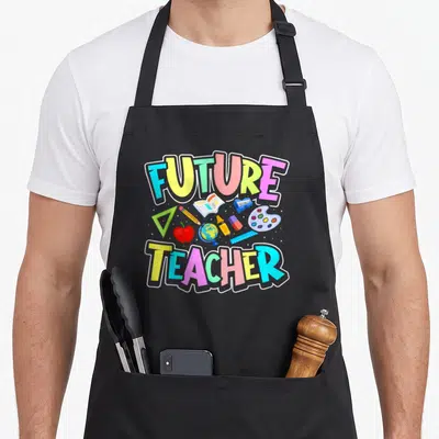 Future career teacher apron - FUTURE TEACHER text with apple globe pencil ruler sharpener eraser crayon palette — shown on a black cotton canvas apron against a white background