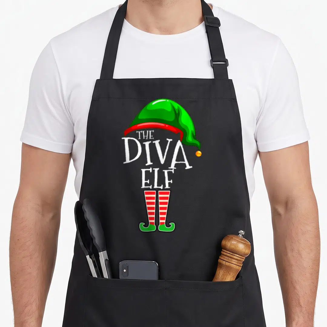 Wife christmas elf apron - The Diva Elf text with green hat and red white striped legs — shown on a black cotton canvas apron against a white background