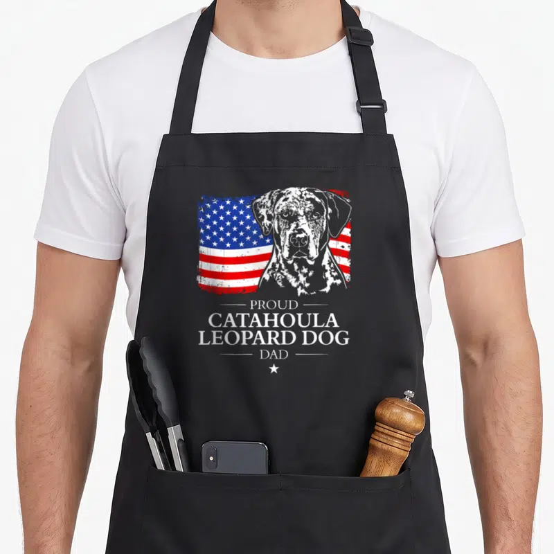 Flag leopard apron - Distressed USA flag behind grey dog portrait with Proud Catahoula Leopard Dog Dad text — shown on a black cotton canvas apron against a white background