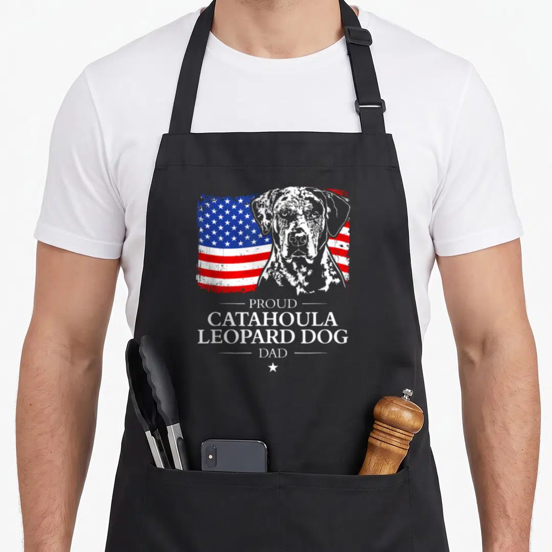 Flag leopard apron - Distressed USA flag behind grey dog portrait with Proud Catahoula Leopard Dog Dad text — shown on a black cotton canvas apron against a white background