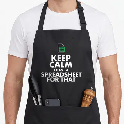 Excel accountant apron - White text KEEP CALM I HAVE A SPREADSHEET FOR THAT below green grid document icon — shown on a black cotton canvas apron against a white background