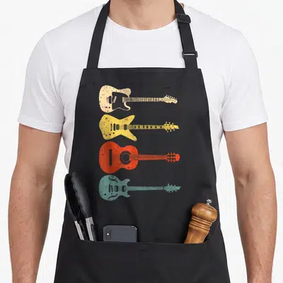 Guitarist acoustics apron - Four distressed guitars in cream, yellow, red, and teal stacked vertically — shown on a black cotton canvas apron against a white background