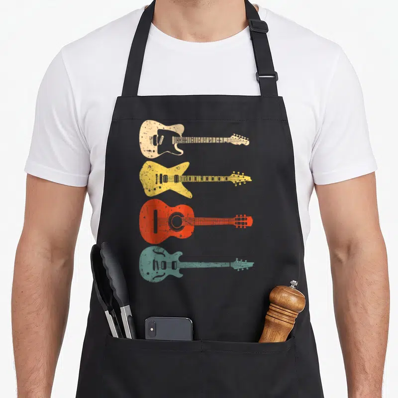 Guitarist acoustics apron - Four distressed guitars in cream, yellow, red, and teal stacked vertically — shown on a black cotton canvas apron against a white background