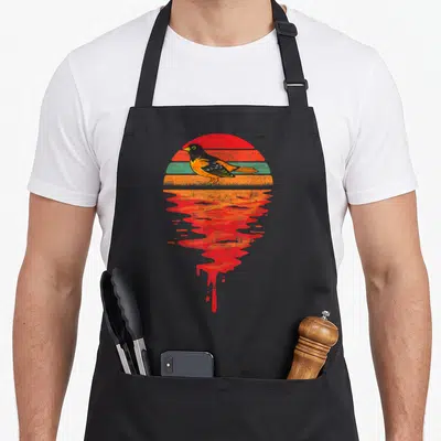 Sunset canary lover apron - Retro Baltimore oriole bird on striped sun with dripping red orange reflection — shown on a black cotton canvas apron against a white background