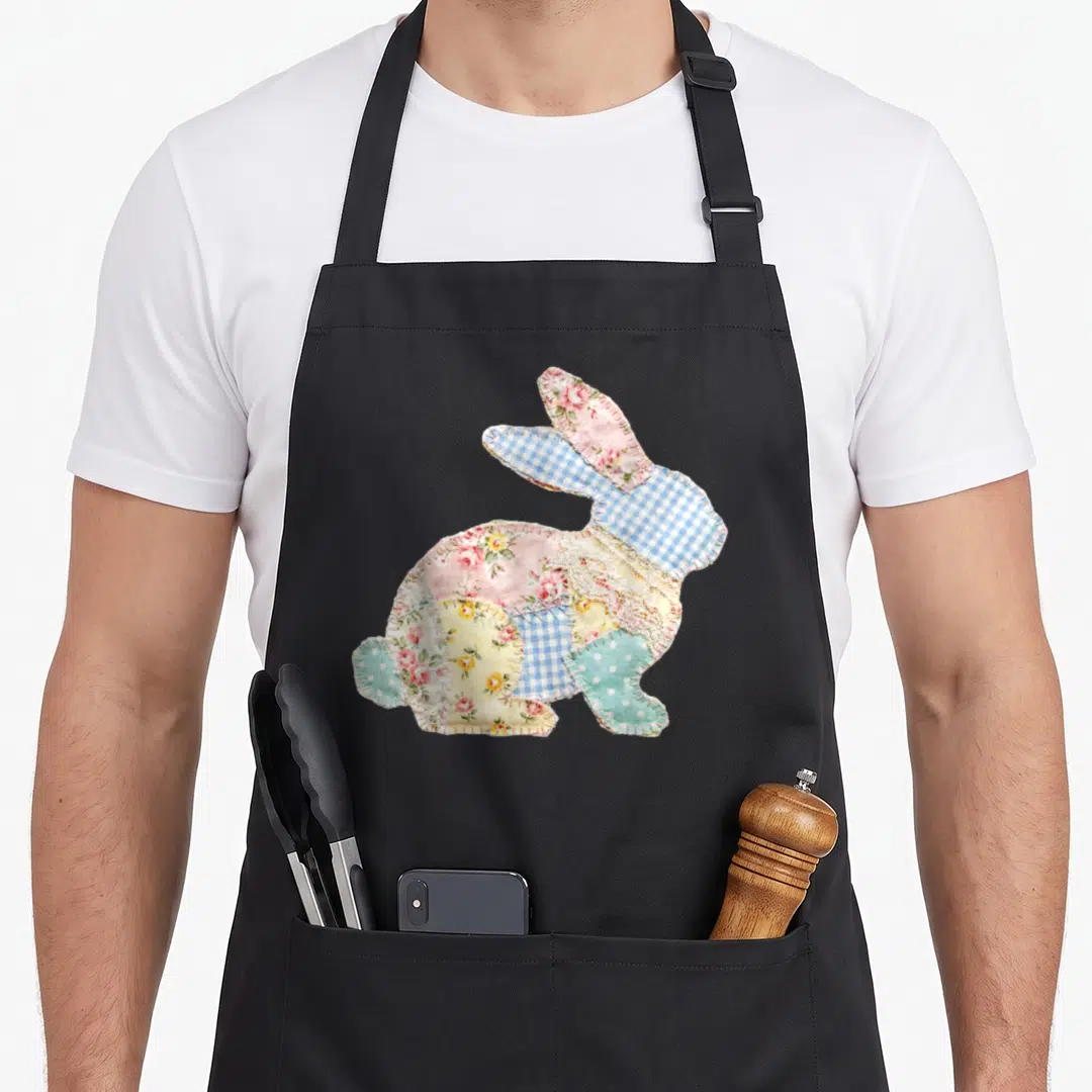Spring cottage apron - Patchwork rabbit silhouette made of pink floral, blue gingham, and lace fabric pieces — shown on a black cotton canvas apron against a white background