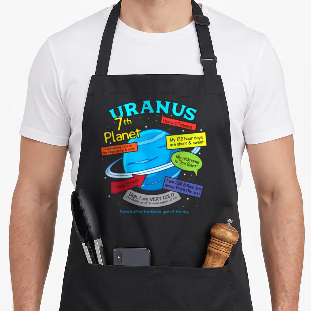Space teaching apron - Uranus planet cartoon with blue rings and colorful fact boxes listing moons and temperature — shown on a black cotton canvas apron against a white background