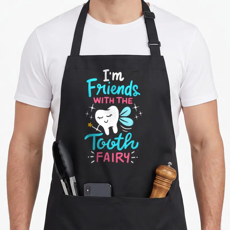Tooth dentist apron - Cartoon tooth fairy holding a star wand with stacked text in blue, pink, white, and yellow — shown on a black cotton canvas apron against a white background