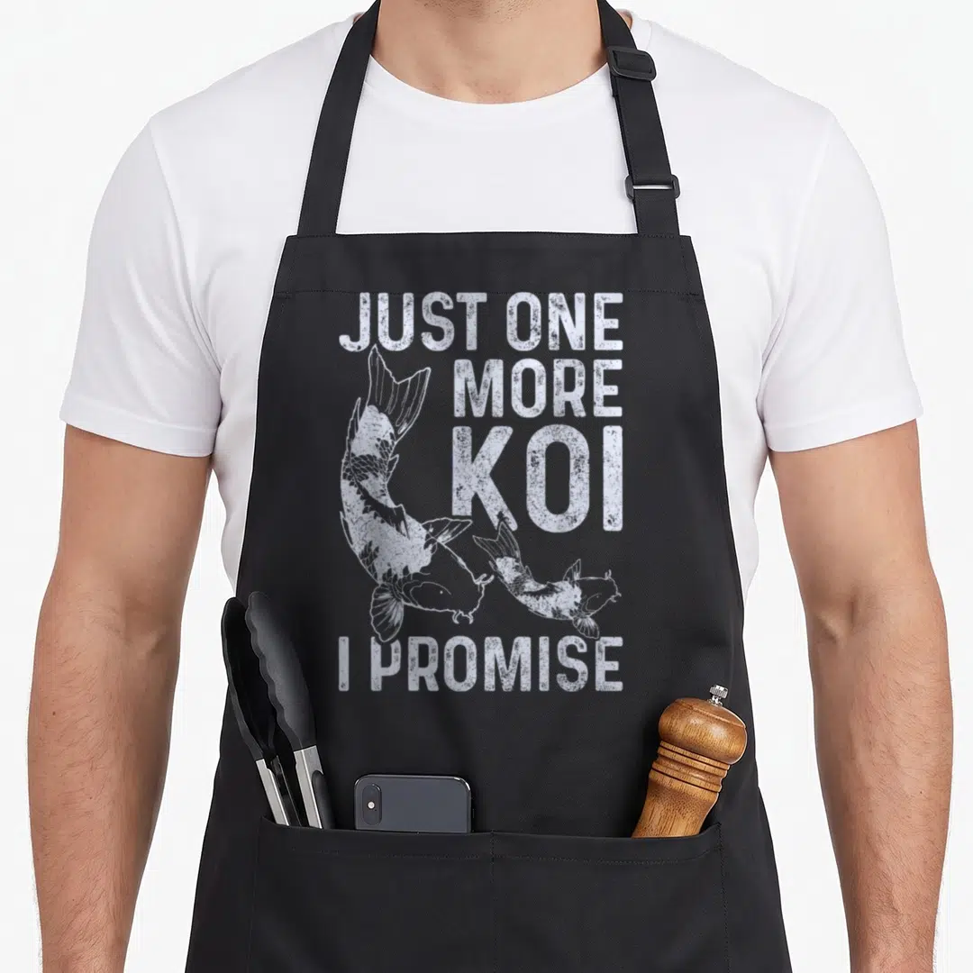 Koi carp japan apron - Distressed white text Just One More Koi I Promise above and below two swimming koi fish — shown on a black cotton canvas apron against a white background