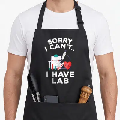 Pre student aprons - Sorry I Can't I Have Lab text with cartoon microscope and test tubes — shown on a black cotton canvas apron against a white background