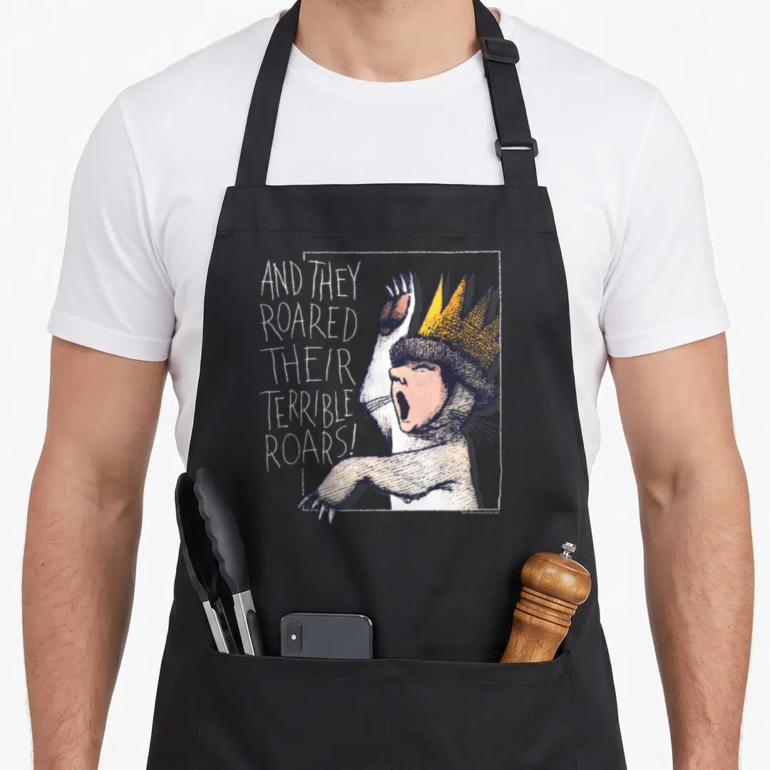 Funny roar wild apron - Crowned monster in line art next to stacked white text AND THEY ROARED THEIR TERRIBLE ROARS! — shown on a black cotton canvas apron against a white background