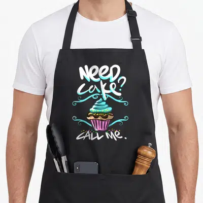 Cake baker apron - Cartoon cupcake with blue frosting and text Need cake Call Me — shown on a black cotton canvas apron against a white background