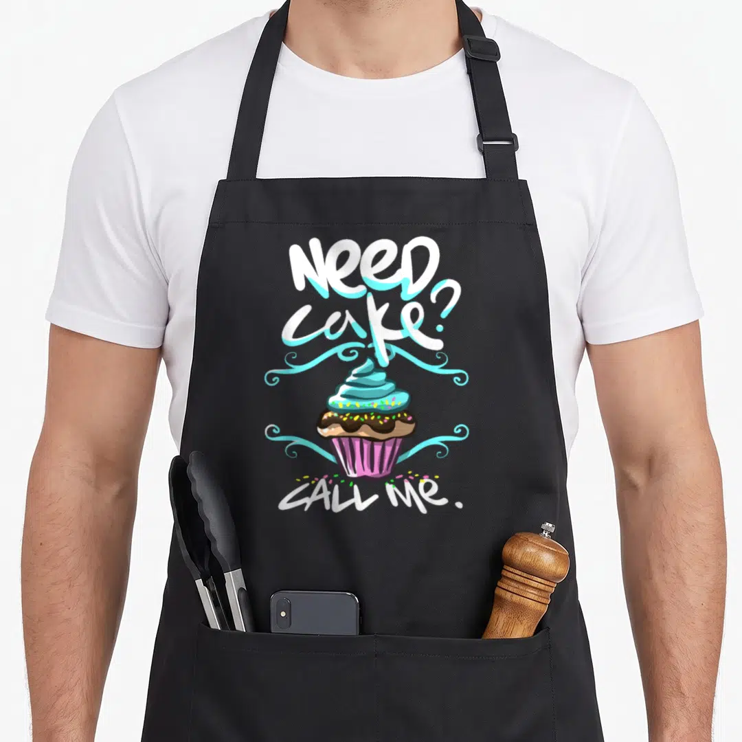 Cake baker apron - Cartoon cupcake with blue frosting and text Need cake Call Me — shown on a black cotton canvas apron against a white background