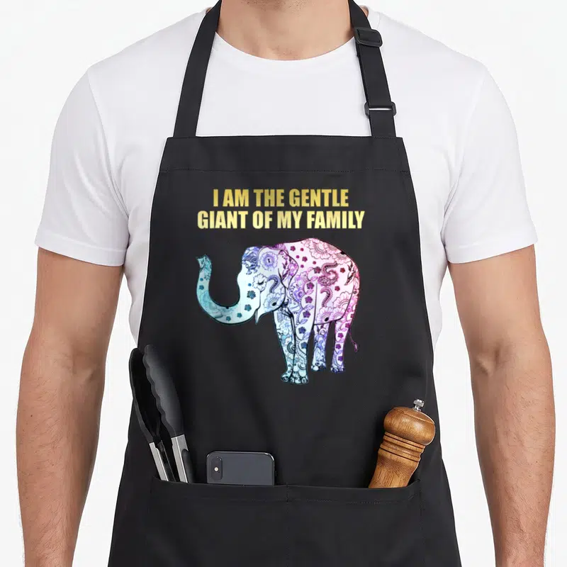 Elephant gentle apron - I AM THE GENTLE GIANT OF MY FAMILY text above a blue purple pink mandala elephant — shown on a black cotton canvas apron against a white background