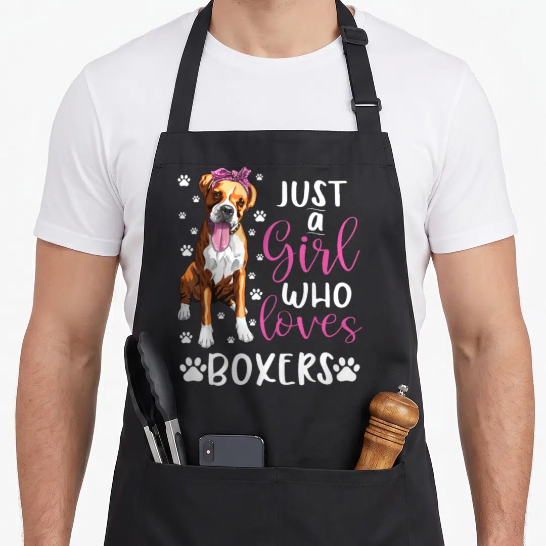 Retro boxer dog apron - Cartoon boxer dog with pink bow and stacked text Just a Girl Who Loves Boxers surrounded by paw — shown on a black cotton canvas apron against a white background