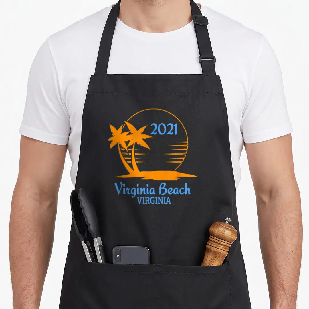 Virginia family aprons - Orange sun with two palm trees and blue 2021 Virginia Beach text — shown on a black cotton canvas apron against a white background