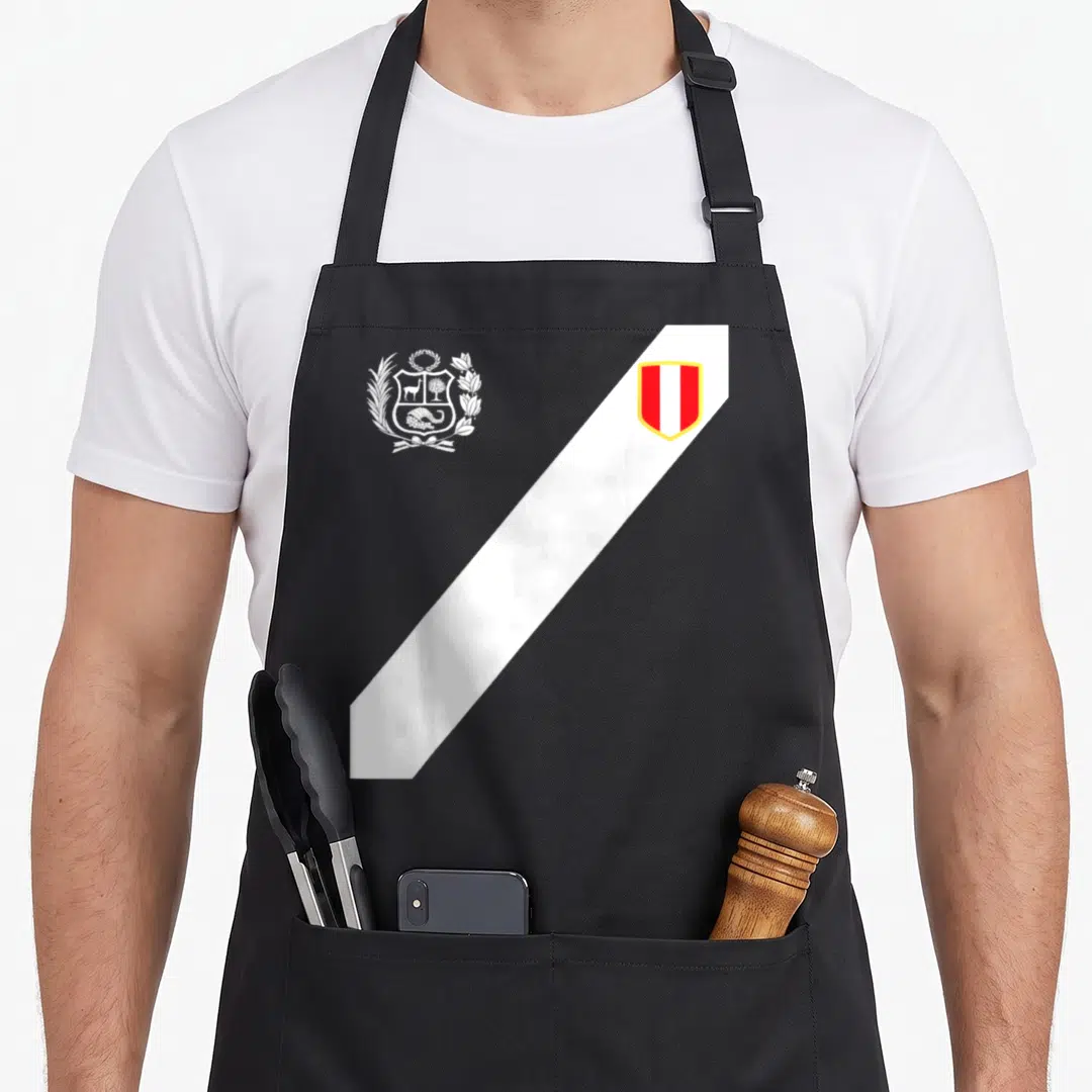 Soccer peruvian apron - White coat of arms and diagonal sash with red and white shield on black background — shown on a black cotton canvas apron against a white background
