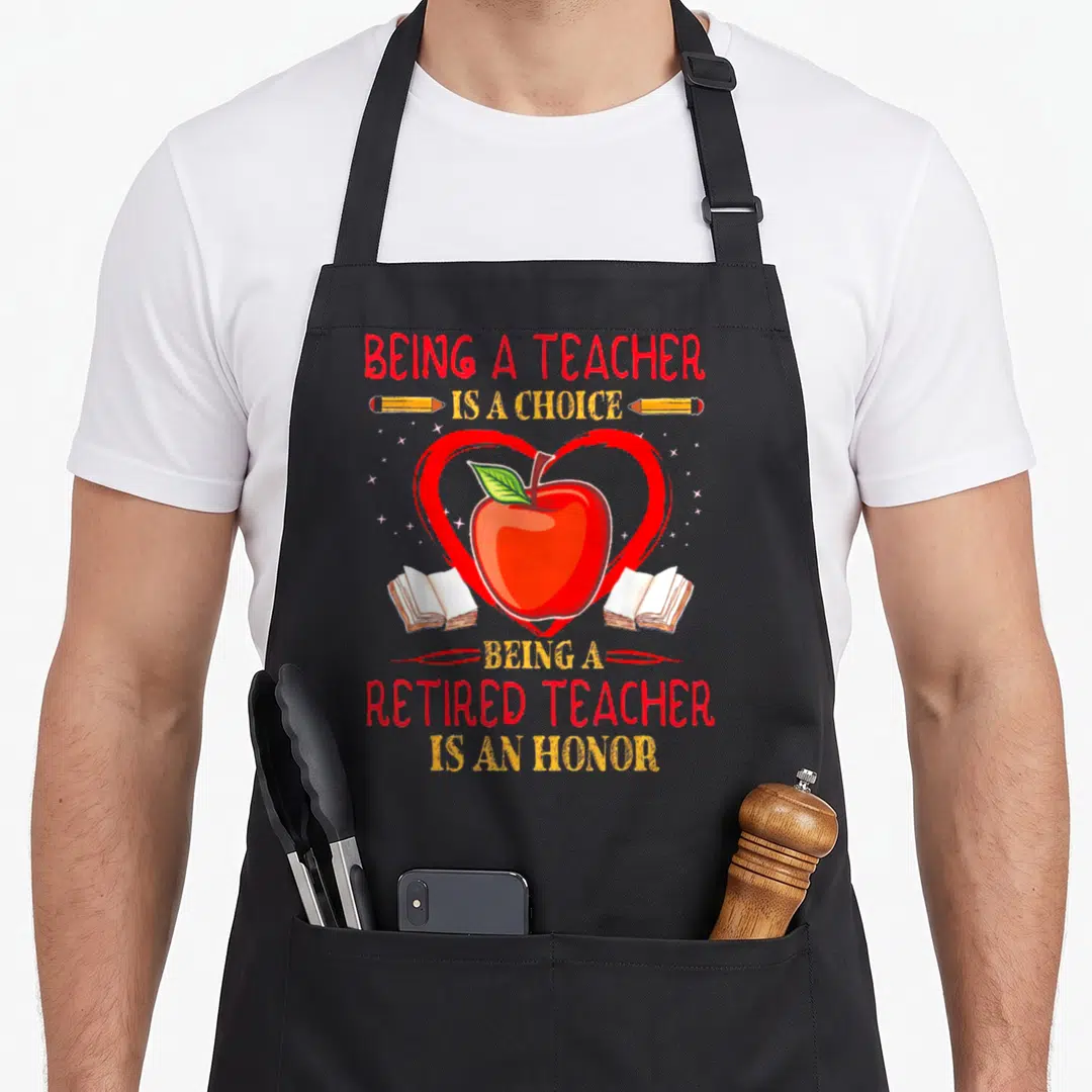 Choice teachers apron - Red apple in heart with books pencils and Being A Teacher Is A Choice text — shown on a black cotton canvas apron against a white background