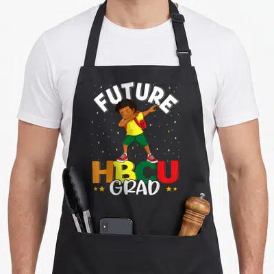 Grad college apron - Cartoon boy dabbing under FUTURE text above HBCU GRAD in yellow green red — shown on a black cotton canvas apron against a white background