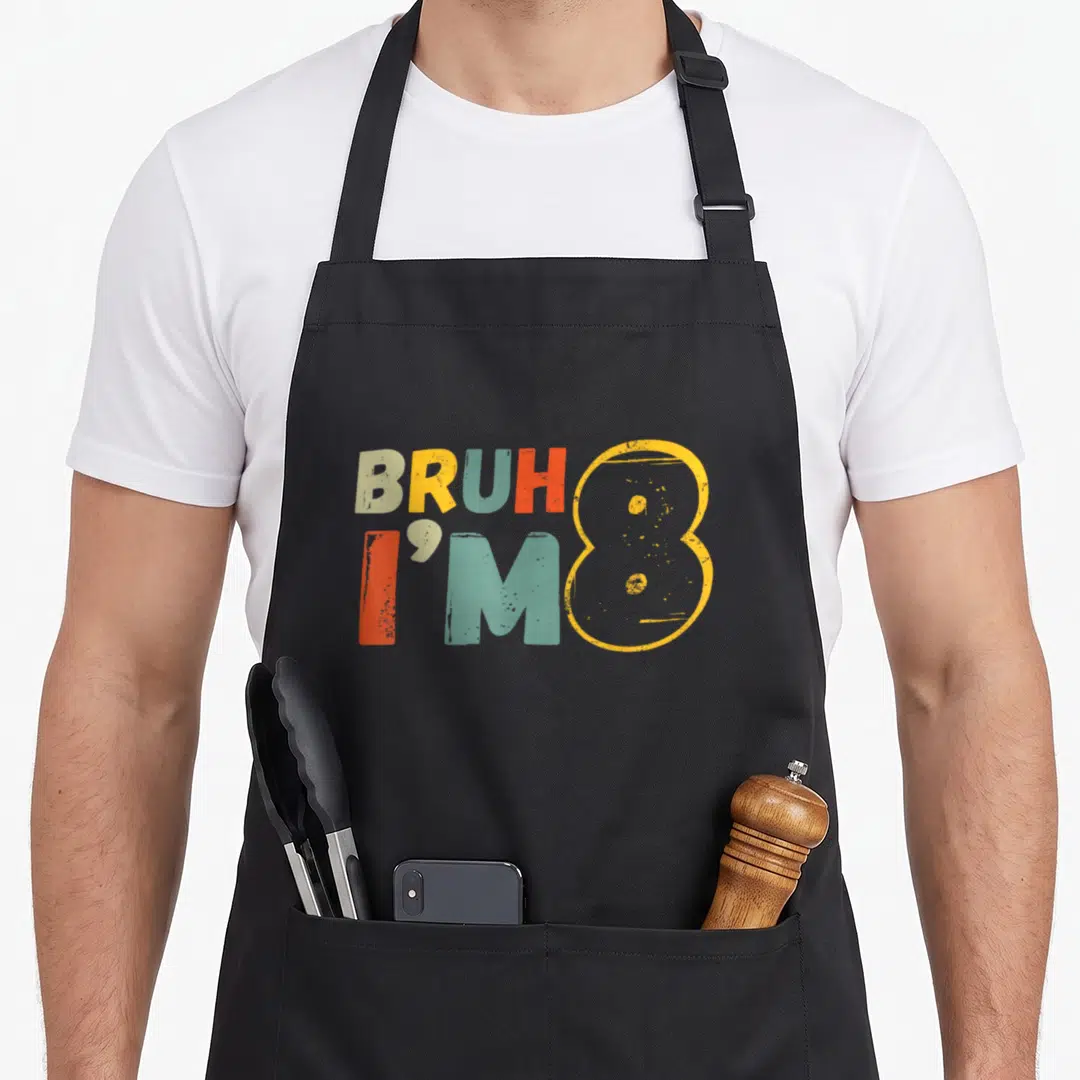 Bruh 8th birthday apron - Stacked text BRUH I'M 8 in beige yellow teal and orange — shown on a black cotton canvas apron against a white background