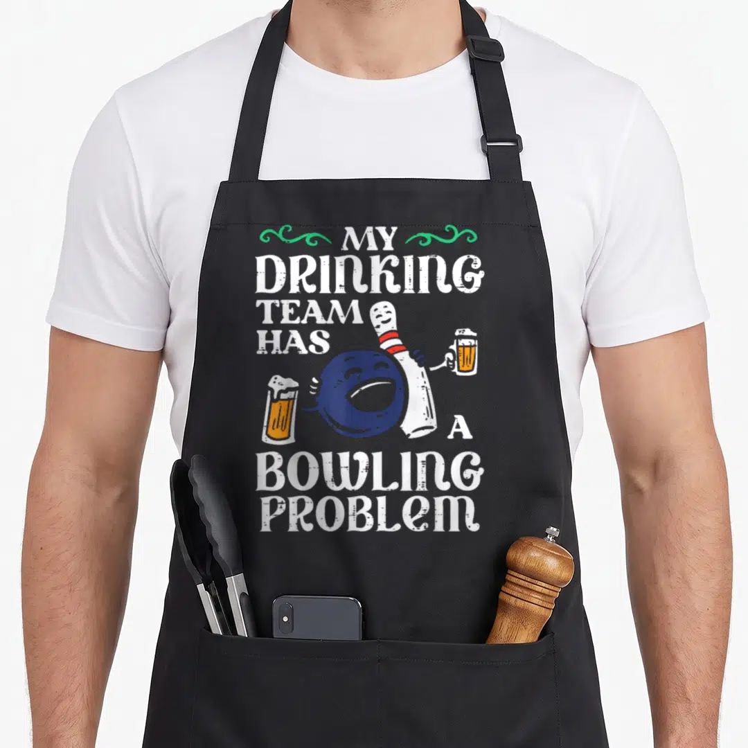 Problem pins for aprons - Cartoon blue bowling ball holding orange beer mug beside white pin with text — shown on a black cotton canvas apron against a white background