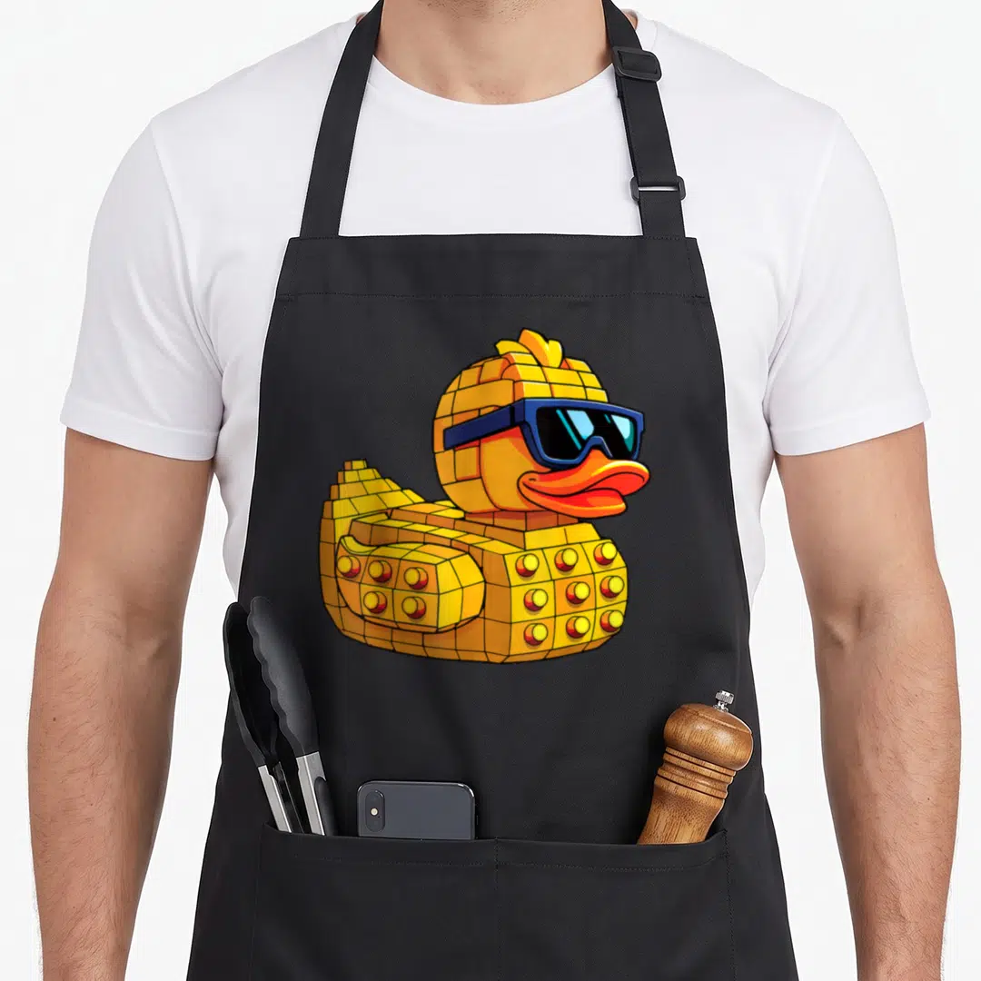 Duck block & apron - Yellow brick rubber duck wearing blue sunglasses with orange beak in cartoon style — shown on a black cotton canvas apron against a white background