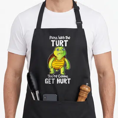 Tortoise box turtle apron - Cartoon green turtle standing between white text Mess With The TURT You're Gonna GET HURT — shown on a black cotton canvas apron against a white background