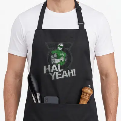 Hal comedian apron - Green Lantern character with HAL YEAH! text in green grey white cartoon style — shown on a black cotton canvas apron against a white background