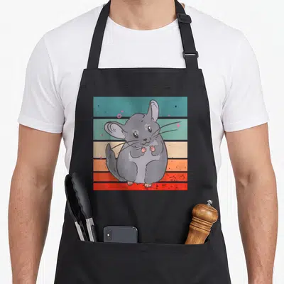 Chinchilla kawaii apron - Grey cartoon chinchilla on teal orange and red horizontal stripes with stars — shown on a black cotton canvas apron against a white background