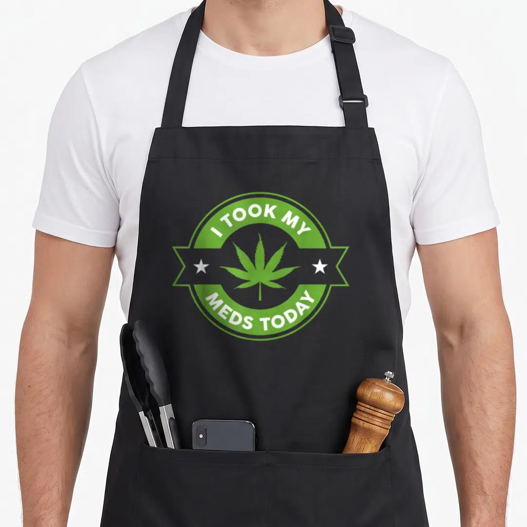 Took hubby apron - Cannabis leaf in green circle with white text and ribbon stars — shown on a black cotton canvas apron against a white background