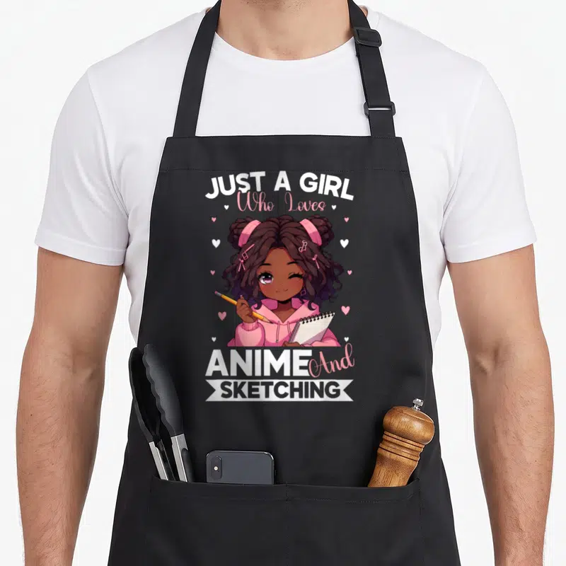 Afro anime apron - Cartoon girl holding pencil and sketchbook with text JUST A GIRL Who Loves ANIME And SKETCHING — shown on a black cotton canvas apron against a white background