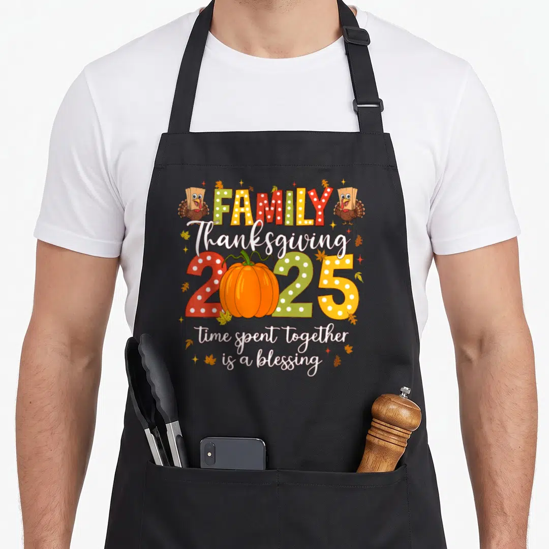 Crew turkey thanksgiving aprons - Cartoon turkeys flank FAMILY text above a pumpkin replacing the zero in 2025 script — shown on a black cotton canvas apron against a white background
