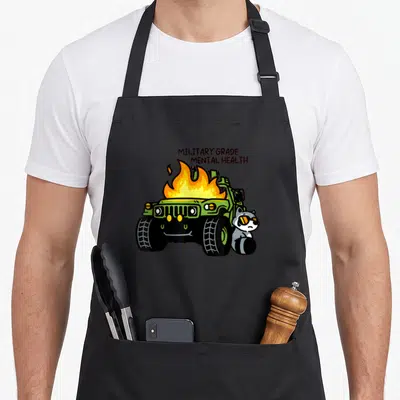 Grade military apron - Burning green military jeep with sunglasses-wearing raccoon and text — shown on a black cotton canvas apron against a white background