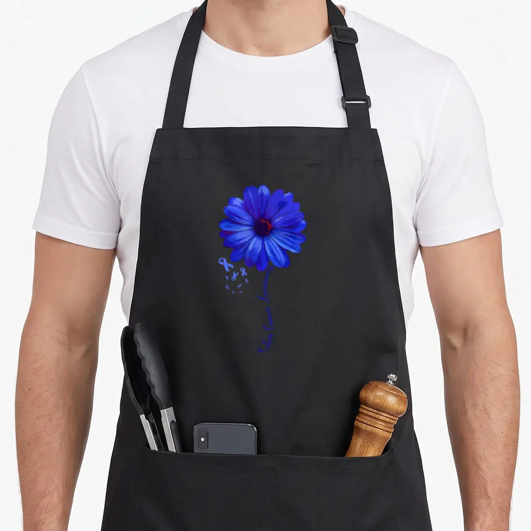 Colon pretty apron - Large blue flower with small ribbons and vertical Colon Cancer Awareness text — shown on a black cotton canvas apron against a white background