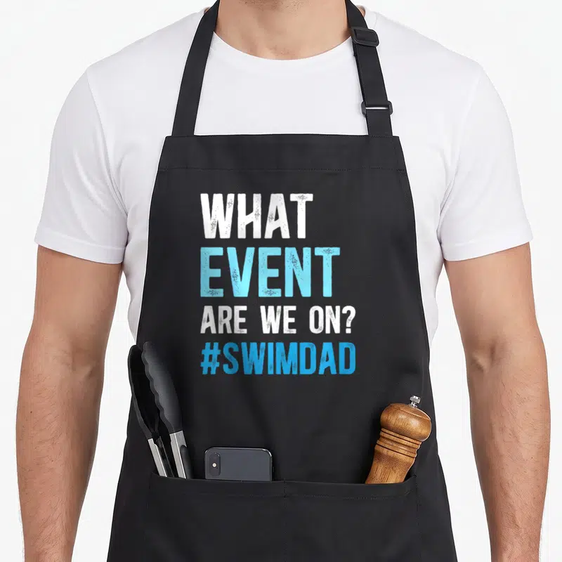 Father swimmer swimming dad apron - White and blue stacked text reading WHAT EVENT ARE WE ON? #SWIMDAD — shown on a black cotton canvas apron against a white background