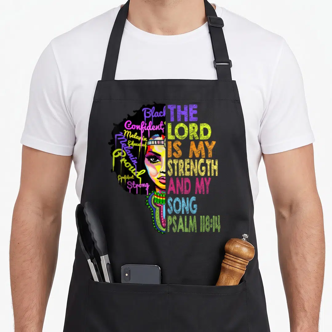 Lord christian apron - Cartoon woman face with afro hair containing words like Black and Proud next to multicolored — shown on a black cotton canvas apron against a white background