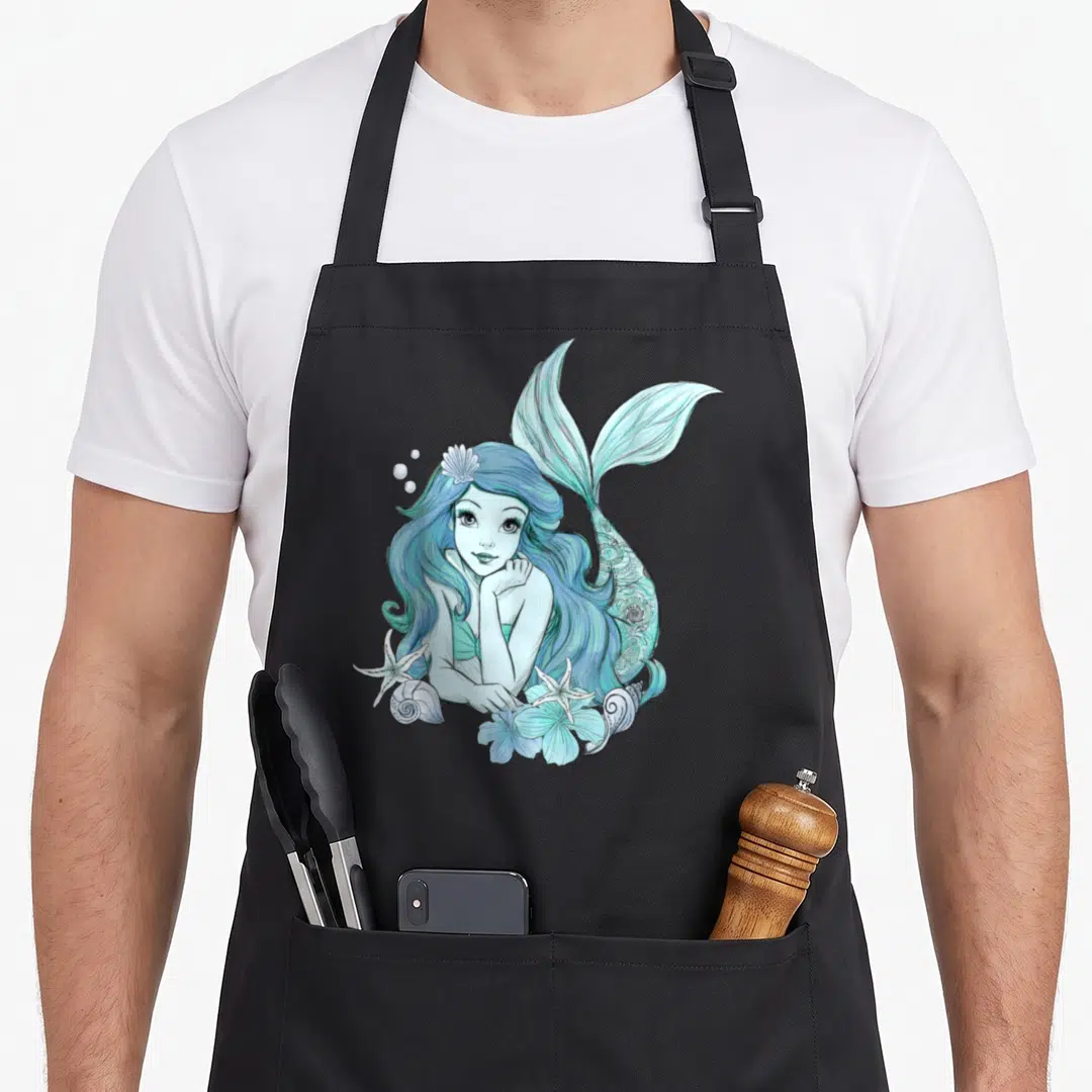 Sketch mermaid apron - Cartoon mermaid in blue and teal with starfish, shells, and bubbles — shown on a black cotton canvas apron against a white background